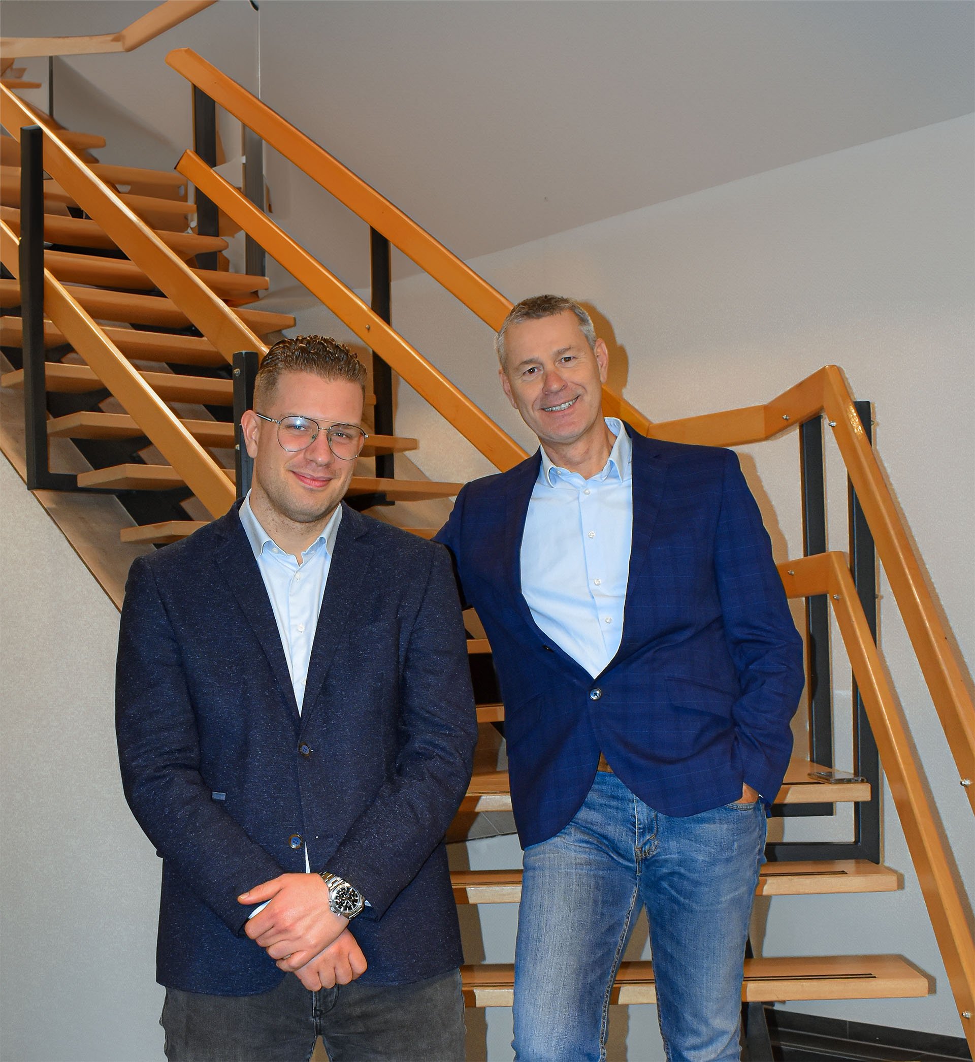 Wesley Koning en Frank Berndt van Candor Verzekeringen samen voor een houten trap op kantoor.