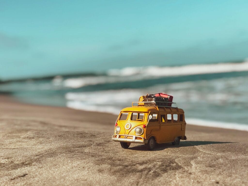 Klein busje op het strand met bagage als symbool voor reizen en een reisverzekering