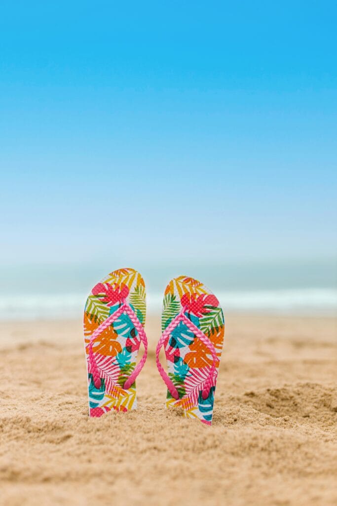 Slippers op het strand als symbool voor zorgeloos op vakantie met een reisverzekering